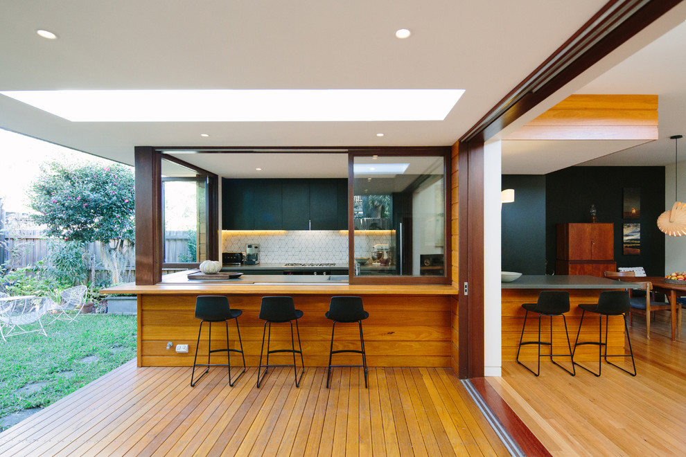 Design ideas for a mid-sized contemporary u-shaped open plan kitchen in Sydney with an integrated sink, flat-panel cabinets, black cabinets, concrete benchtops, white splashback, medium hardwood floors and no island.