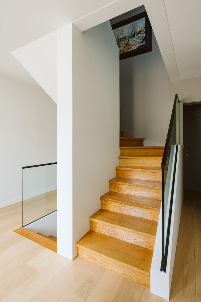 Mid-sized contemporary wood u-shaped staircase in Lille with wood risers and glass railing.