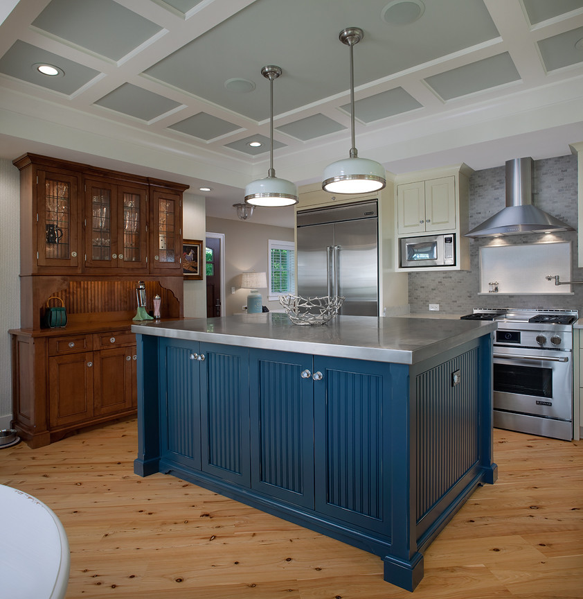 This is an example of a large traditional l-shaped eat-in kitchen in Grand Rapids with an undermount sink, recessed-panel cabinets, blue cabinets, stainless steel benchtops, grey splashback, stainless steel appliances, light hardwood floors and with island.
