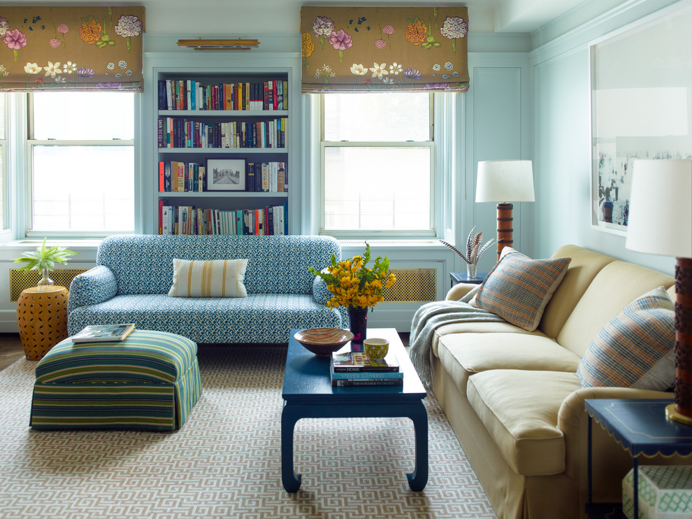 This is an example of a transitional family room in New York with a library and blue walls.