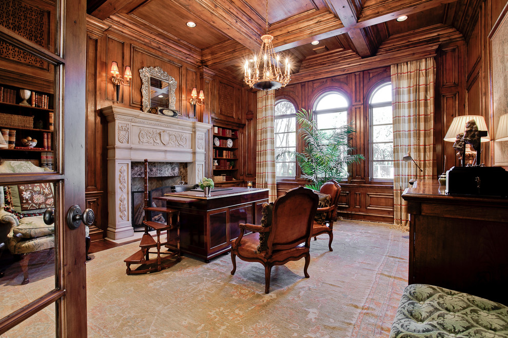 This is an example of a mediterranean home office in Dallas with dark hardwood floors, a standard fireplace and a freestanding desk.