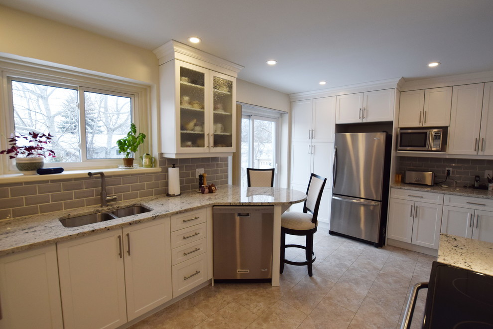 Inspiration for a mid-sized transitional u-shaped ceramic tile enclosed kitchen remodel in Ottawa with an undermount sink, shaker cabinets, white cabinets, granite countertops, gray backsplash, glass tile backsplash, stainless steel appliances and a peninsula