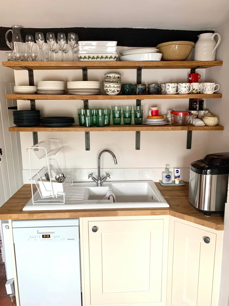 This is an example of a small traditional u-shaped separate kitchen in Other with a double-bowl sink, shaker cabinets, white cabinets, wood benchtops, white splashback, ceramic splashback, white appliances, terra-cotta floors, no island, red floor, brown benchtop and exposed beam.