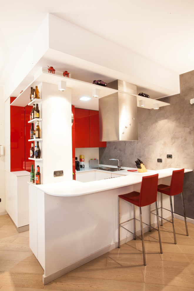Inspiration for a small contemporary u-shaped eat-in kitchen in Milan with flat-panel cabinets, red cabinets, no island, light hardwood floors and a drop-in sink.