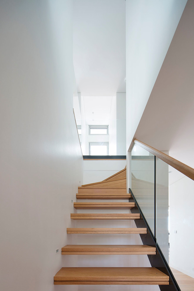 This is an example of a mid-sized modern wood l-shaped staircase in Sydney with open risers and mixed railing.