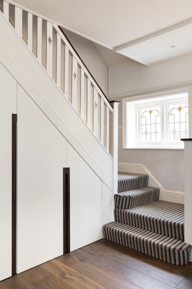 This is an example of a mid-sized modern carpeted u-shaped staircase in Surrey with carpet risers and wood railing.
