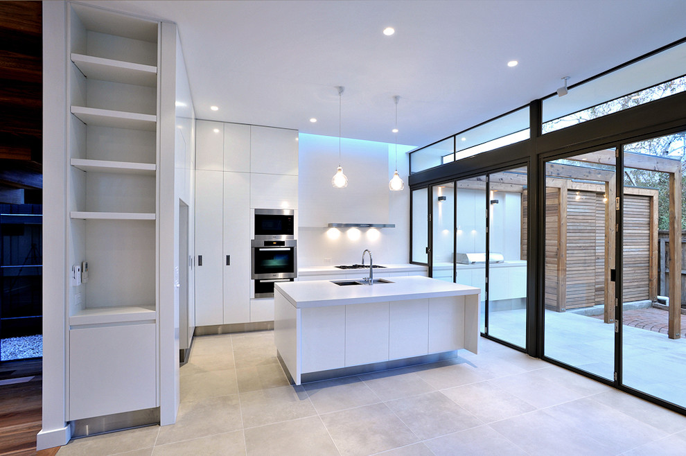Inspiration for a mid-sized contemporary l-shaped kitchen pantry in Melbourne with an undermount sink, flat-panel cabinets, white cabinets, quartz benchtops, white splashback, glass sheet splashback, stainless steel appliances, ceramic floors and with island.