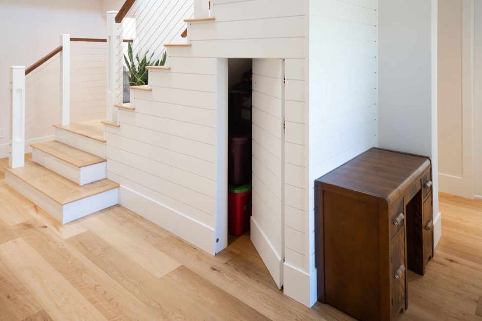 Photo of a country wood l-shaped staircase in Vancouver with cable railing and planked wall panelling.