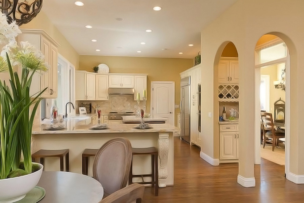 Transitional u-shaped medium tone wood floor eat-in kitchen photo in Cincinnati with a farmhouse sink, raised-panel cabinets, white cabinets, marble countertops, white backsplash, stone tile backsplash, stainless steel appliances and an island