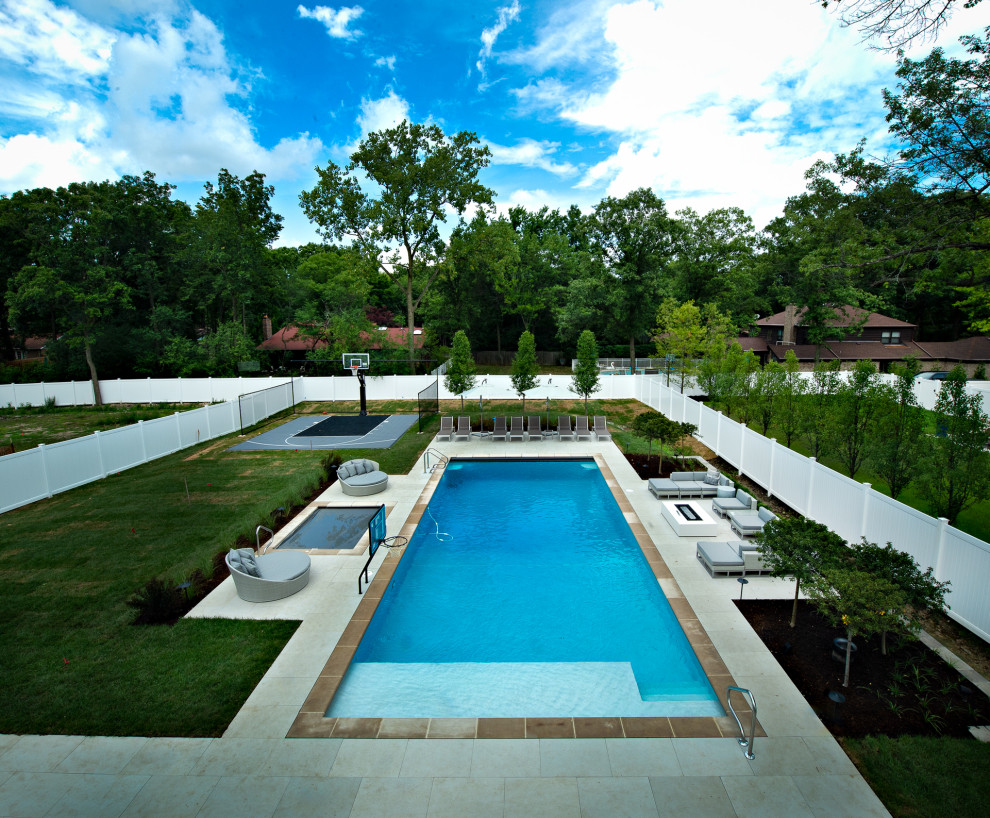 Large country backyard rectangular lap pool in Chicago with a hot tub and concrete pavers.