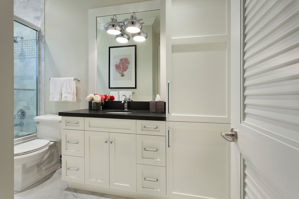 Mid-sized transitional master marble floor and multicolored floor alcove bathtub photo in Miami with recessed-panel cabinets, white cabinets, a one-piece toilet, beige walls, an undermount sink, granite countertops, a hinged shower door and black countertops