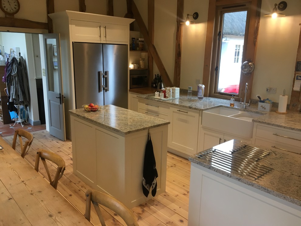Large traditional open plan kitchen in Wiltshire with shaker cabinets, granite benchtops and multiple islands.