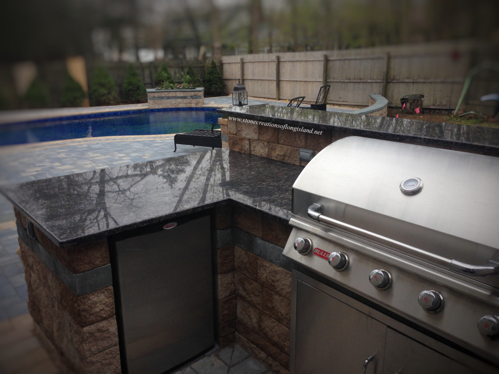 Large beach style backyard patio in New York with an outdoor kitchen, concrete pavers and no cover.