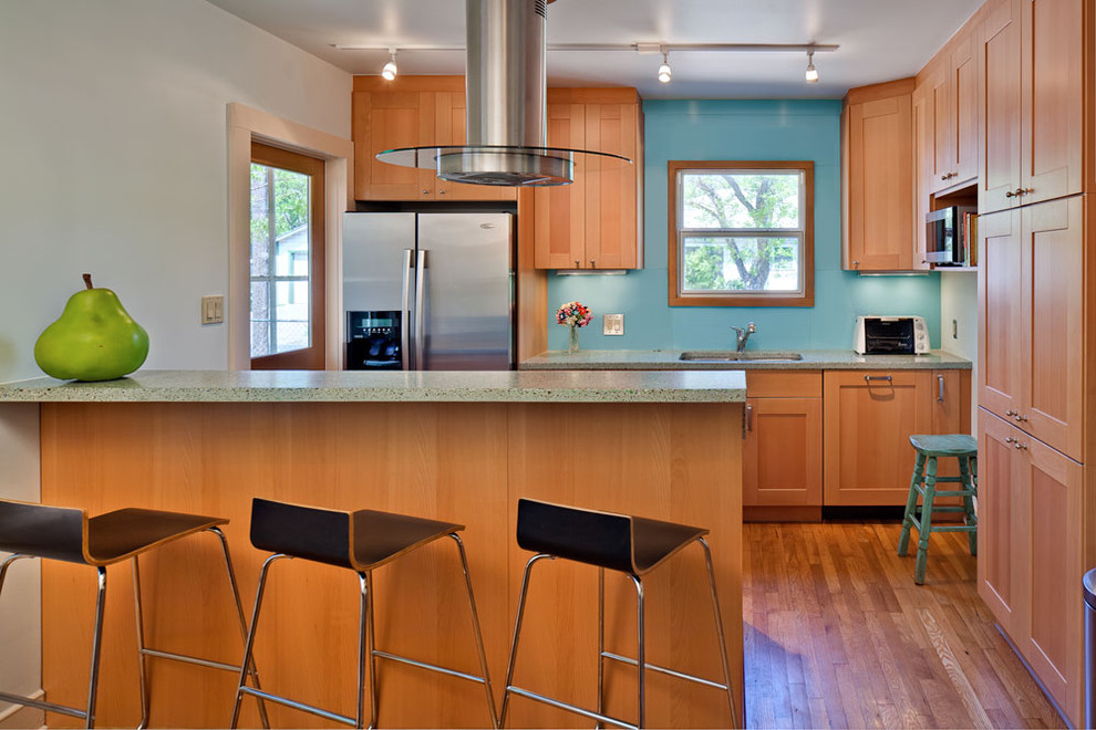 This is an example of a contemporary galley kitchen in Austin with stainless steel appliances and medium wood cabinets.