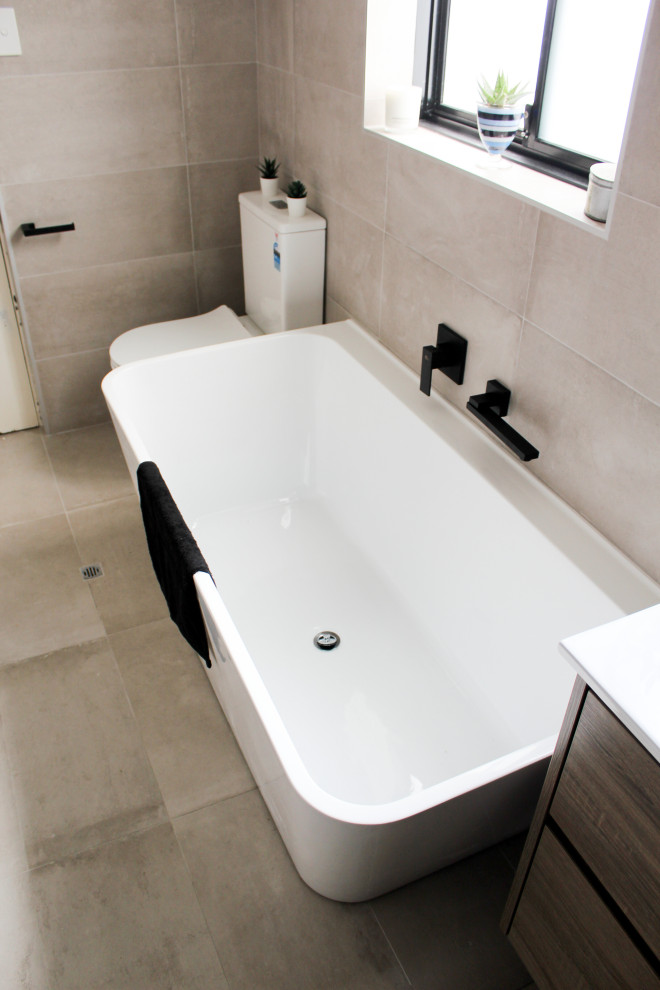 Inspiration for a large 3/4 bathroom in Perth with flat-panel cabinets, dark wood cabinets, a freestanding tub, an alcove shower, a one-piece toilet, gray tile, porcelain tile, grey walls, porcelain floors, an integrated sink, solid surface benchtops, grey floor, a hinged shower door and white benchtops.