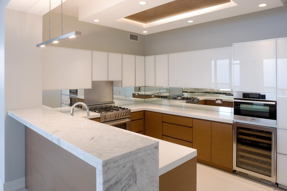 Small contemporary galley separate kitchen in Chicago with an undermount sink, glass-front cabinets, medium wood cabinets, solid surface benchtops, mirror splashback, stainless steel appliances, concrete floors, white floor, white benchtop and wood.