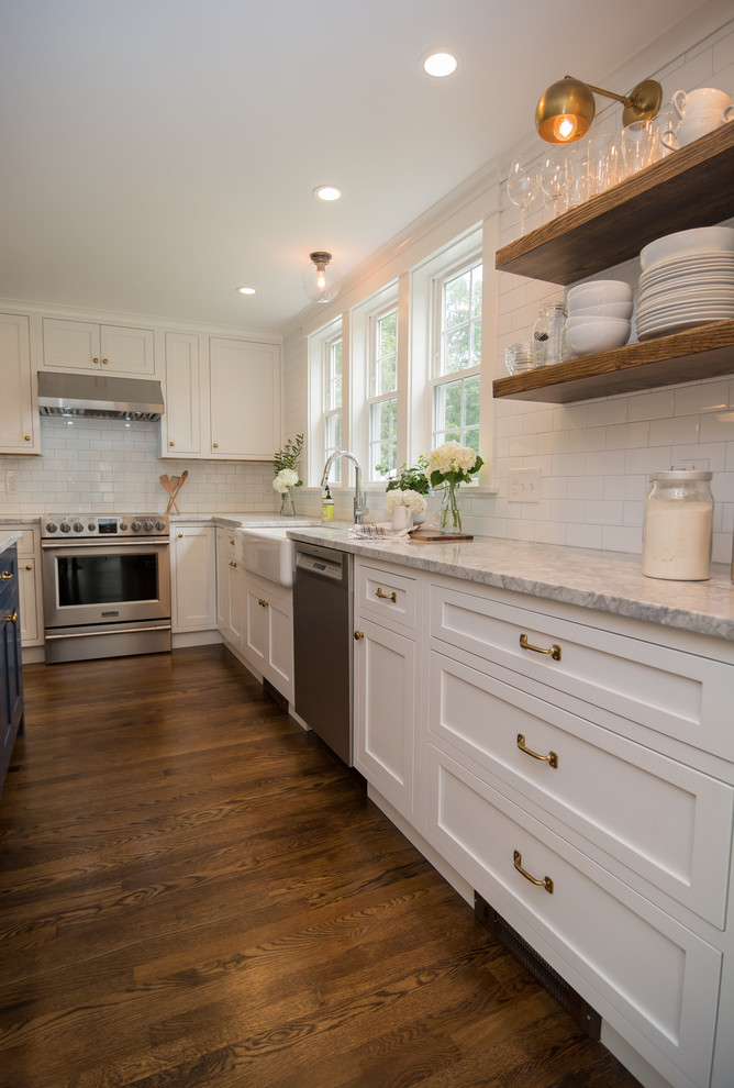 Mid-sized country l-shaped eat-in kitchen in Boston with a farmhouse sink, shaker cabinets, white cabinets, quartzite benchtops, white splashback, ceramic splashback, stainless steel appliances, dark hardwood floors, with island, brown floor and grey benchtop.