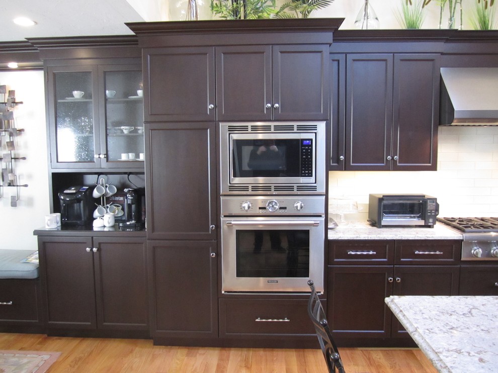 Example of a large transitional l-shaped light wood floor eat-in kitchen design with shaker cabinets, black cabinets, marble countertops, white backsplash, subway tile backsplash, stainless steel appliances and an island