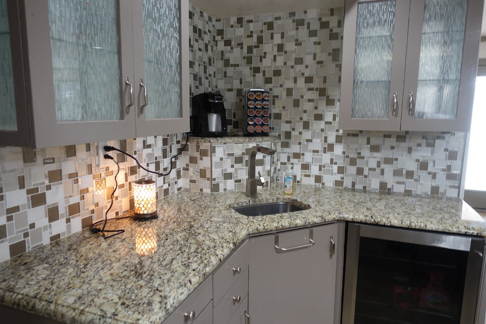 Design ideas for a mid-sized transitional l-shaped wet bar in Austin with an undermount sink, flat-panel cabinets, grey cabinets, granite benchtops, multi-coloured splashback, glass tile splashback and beige benchtop.