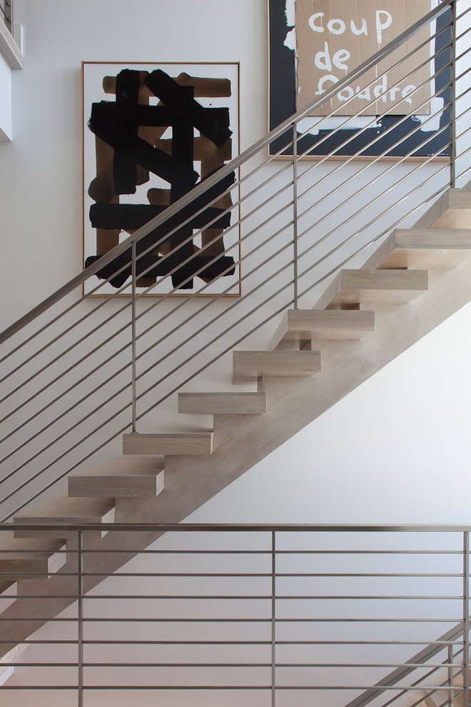 Photo of a mid-sized contemporary wood floating staircase in Other with open risers and metal railing.