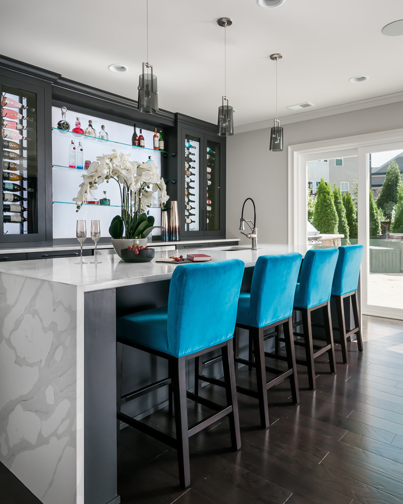 Inspiration for an expansive contemporary galley seated home bar in Atlanta with an undermount sink, flat-panel cabinets, black cabinets, quartz benchtops, dark hardwood floors, brown floor, white benchtop and glass sheet splashback.