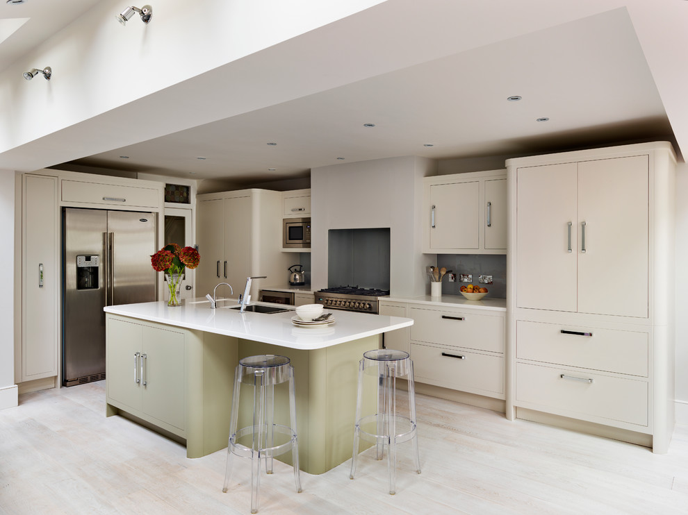 This is an example of a mid-sized contemporary l-shaped kitchen in London with an undermount sink, flat-panel cabinets, beige cabinets, grey splashback, glass sheet splashback, stainless steel appliances and with island.