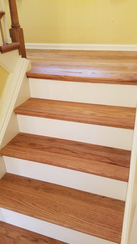 This is an example of a large traditional wood l-shaped staircase in New York with wood risers and wood railing.