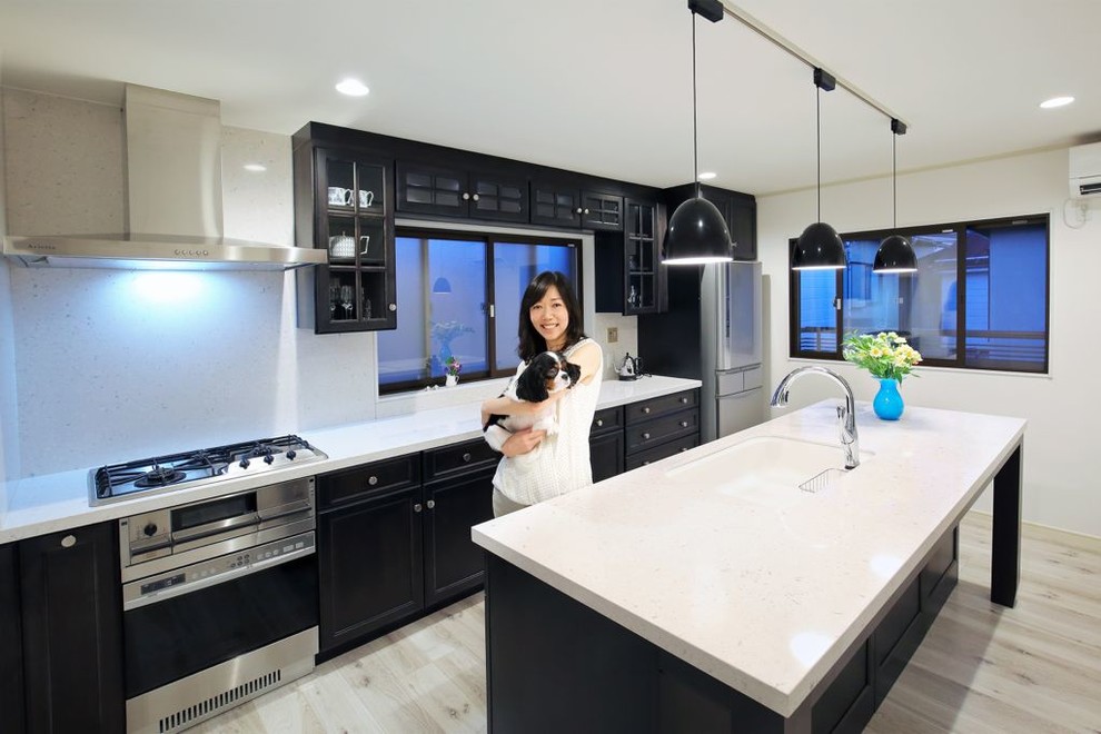 Photo of a large contemporary single-wall eat-in kitchen in Tokyo with an undermount sink, recessed-panel cabinets, black cabinets, soapstone benchtops, white splashback, stone slab splashback, stainless steel appliances, light hardwood floors and with island.