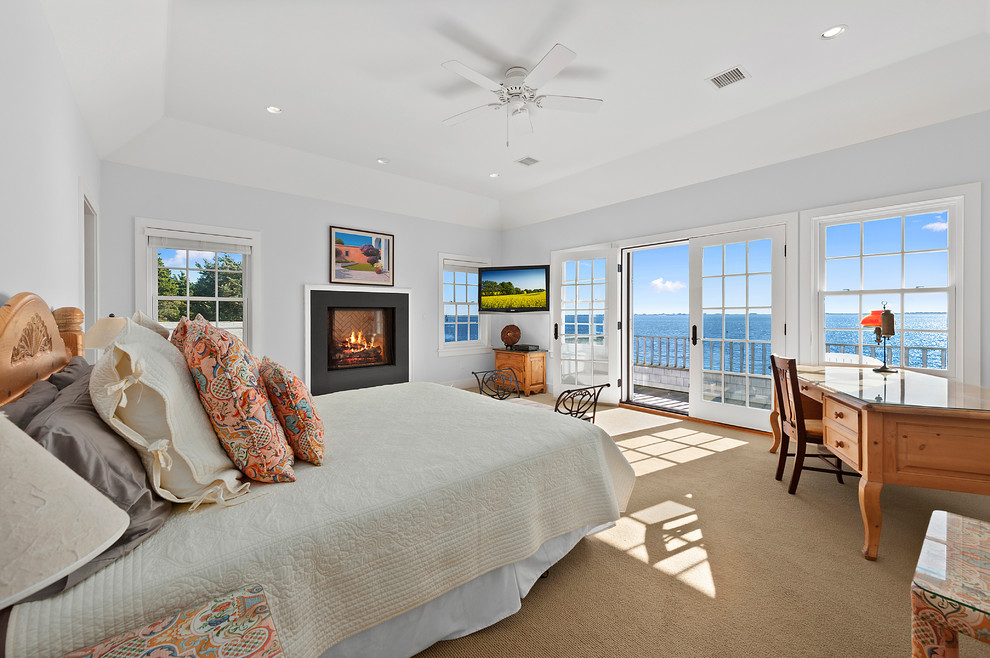 Design ideas for an expansive beach style master bedroom in New York with carpet and a standard fireplace.