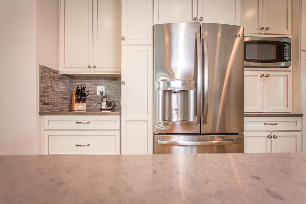 Transitional u-shaped kitchen photo in DC Metro with an undermount sink, flat-panel cabinets, white cabinets, quartz countertops, gray backsplash and stainless steel appliances