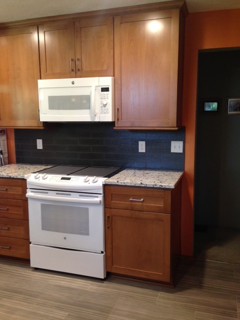 Transitional porcelain tile kitchen photo in Seattle with an undermount sink, shaker cabinets, medium tone wood cabinets, quartz countertops, gray backsplash, glass tile backsplash and white appliances