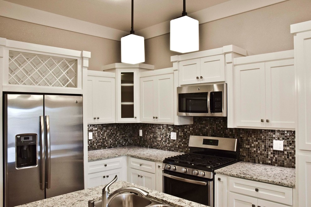 Home design - mid-sized transitional u-shaped ceramic tile home design idea in Austin with a double-bowl sink, flat-panel cabinets, white cabinets, granite countertops, metallic backsplash, glass tile backsplash, stainless steel appliances and an island