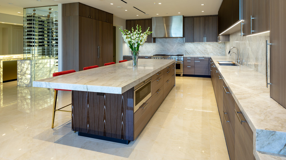 Inspiration for an expansive contemporary open plan kitchen in Houston with a triple-bowl sink, flat-panel cabinets, grey cabinets, quartzite benchtops, beige splashback, stone slab splashback, stainless steel appliances, porcelain floors, beige floor and beige benchtop.