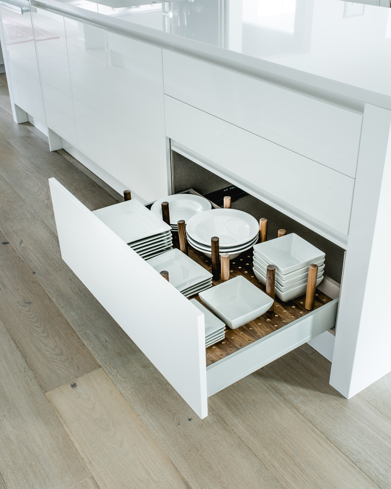 Photo of a mid-sized contemporary l-shaped eat-in kitchen in Dallas with an undermount sink, flat-panel cabinets, white cabinets, quartz benchtops, white splashback, stone slab splashback, stainless steel appliances, light hardwood floors and multiple islands.