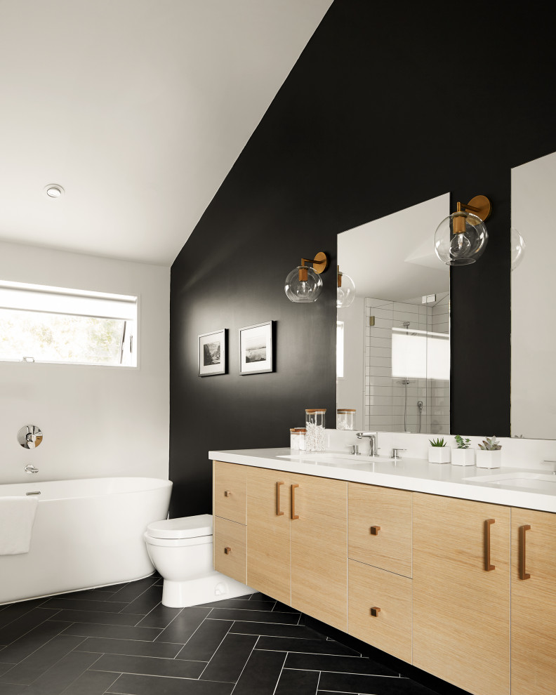 Photo of a mid-sized contemporary master bathroom in San Francisco with flat-panel cabinets, light wood cabinets, a freestanding tub, a corner shower, a one-piece toilet, black and white tile, ceramic tile, white walls, porcelain floors, a drop-in sink, engineered quartz benchtops, black floor, a hinged shower door, white benchtops, a niche, a double vanity, a built-in vanity and vaulted.