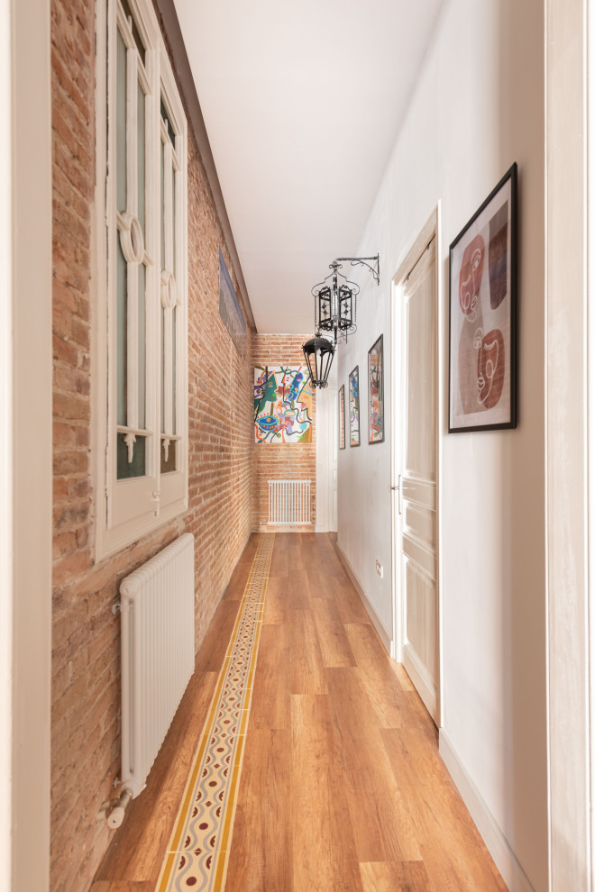 Inspiration for a mid-sized transitional hallway in Barcelona with white walls, vinyl floors, multi-coloured floor, exposed beam and brick walls.