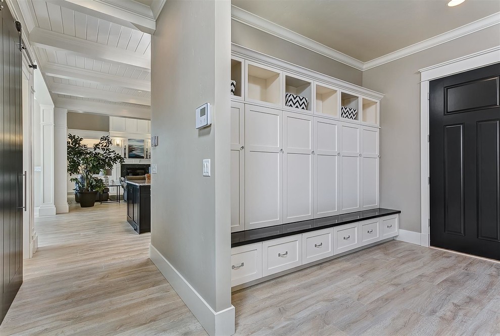 This is an example of a large traditional mudroom in Boise with beige walls, light hardwood floors, a single front door and a black front door.
