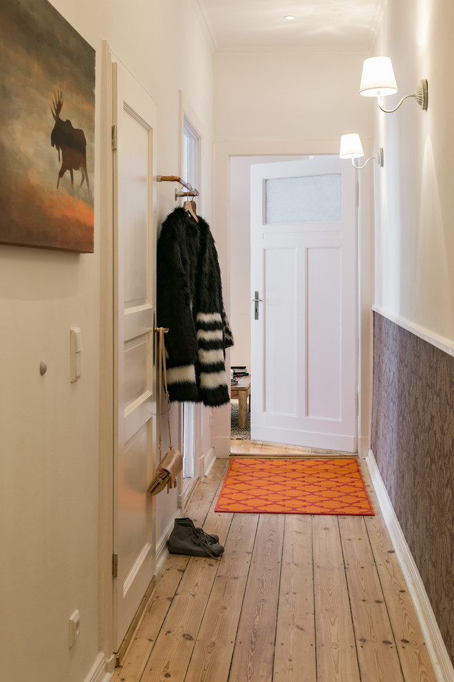 Photo of a mid-sized traditional hallway in Berlin with white walls, medium hardwood floors and brown floor.