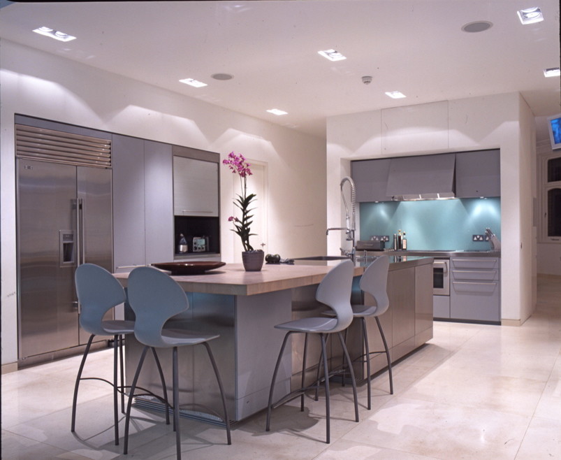 Design ideas for a contemporary eat-in kitchen in London with recessed-panel cabinets, stainless steel benchtops, stainless steel appliances and with island.