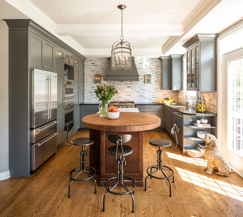 Mid-sized traditional u-shaped eat-in kitchen in Ottawa with grey splashback, stainless steel appliances, medium hardwood floors, with island, an undermount sink, recessed-panel cabinets, grey cabinets, matchstick tile splashback and brown floor.