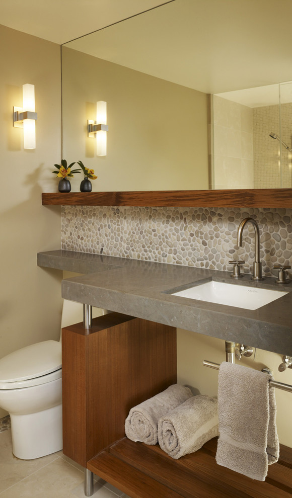This is an example of a mid-sized contemporary 3/4 bathroom in San Francisco with an undermount sink, pebble tile, beige walls, ceramic floors, open cabinets, medium wood cabinets, a two-piece toilet, gray tile and beige floor.
