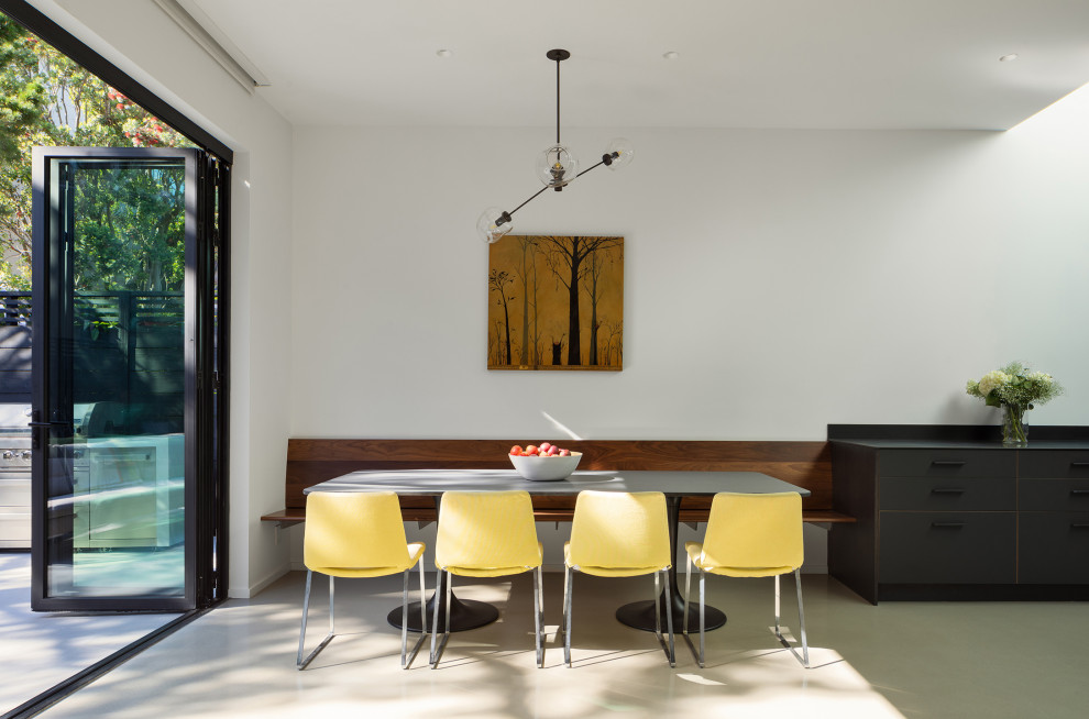 На фото: столовая в современном стиле с с кухонным уголком, белыми стенами, бетонным полом и серым полом