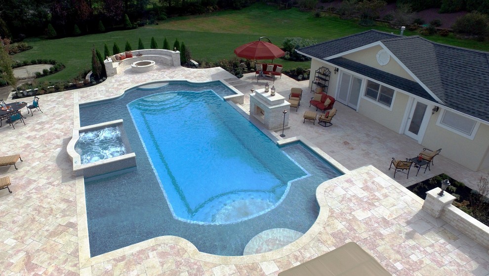 Example of a large backyard stone and custom-shaped lap hot tub design in New York