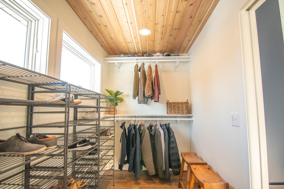 Inspiration for an expansive classic gender neutral walk-in wardrobe in Minneapolis with light hardwood flooring, brown floors and a timber clad ceiling.