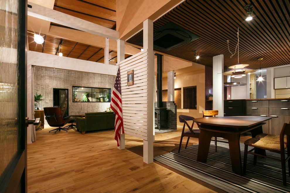 Photo of a midcentury open plan dining in Other with light hardwood floors, a wood stove and a stone fireplace surround.