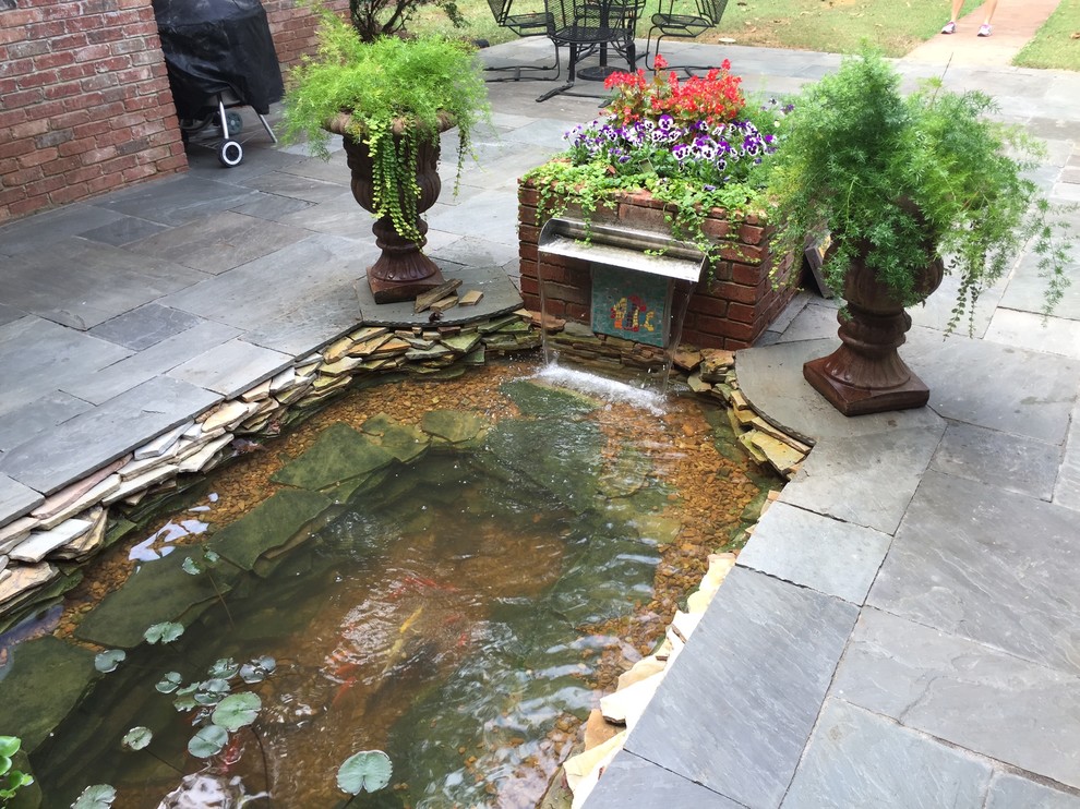This is an example of an asian backyard formal garden in Other with with pond and natural stone pavers.
