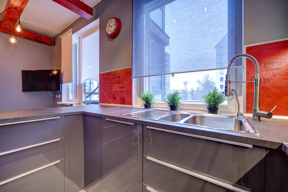 На фото: большая п-образная кухня в современном стиле с обеденным столом, двойной мойкой, плоскими фасадами, серыми фасадами, столешницей из ламината, красным фартуком, полом из керамической плитки и полуостровом с