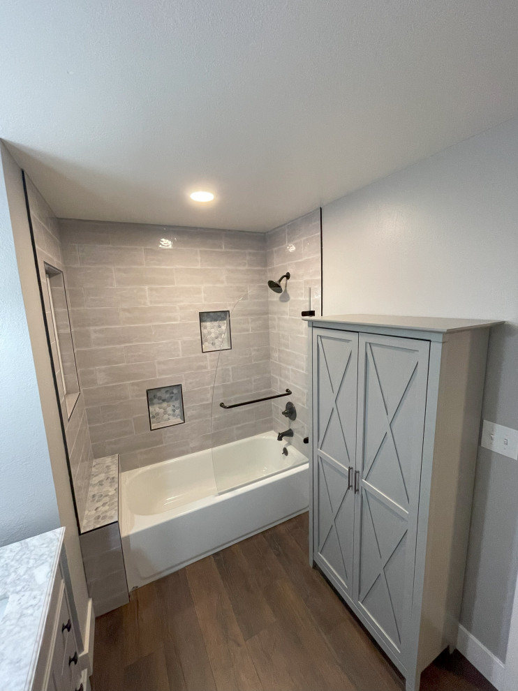 This is an example of a small transitional kids bathroom in San Francisco with flat-panel cabinets, grey cabinets, an alcove tub, a shower/bathtub combo, a two-piece toilet, gray tile, ceramic tile, grey walls, vinyl floors, an undermount sink, marble benchtops, brown floor, a hinged shower door, multi-coloured benchtops, a shower seat, a single vanity and a freestanding vanity.