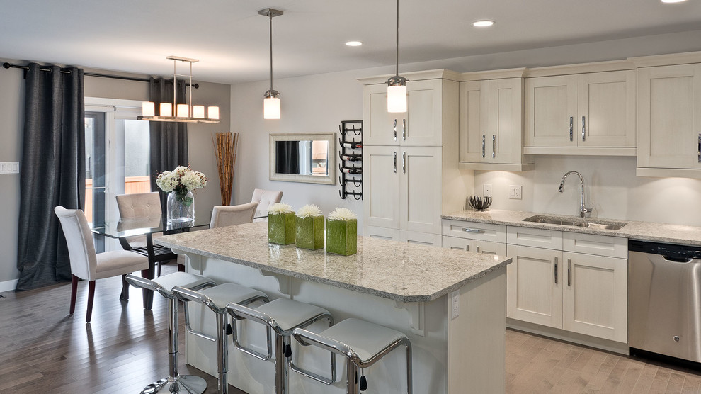Example of a mid-sized transitional single-wall light wood floor eat-in kitchen design with a double-bowl sink, recessed-panel cabinets, white cabinets, granite countertops, white backsplash, stainless steel appliances and an island