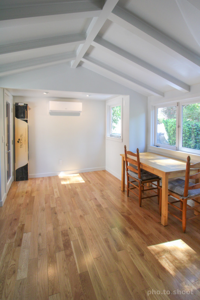 Imagen de sala de manualidades abovedada y blanca tradicional de tamaño medio con paredes blancas, suelo laminado, escritorio independiente y suelo marrón